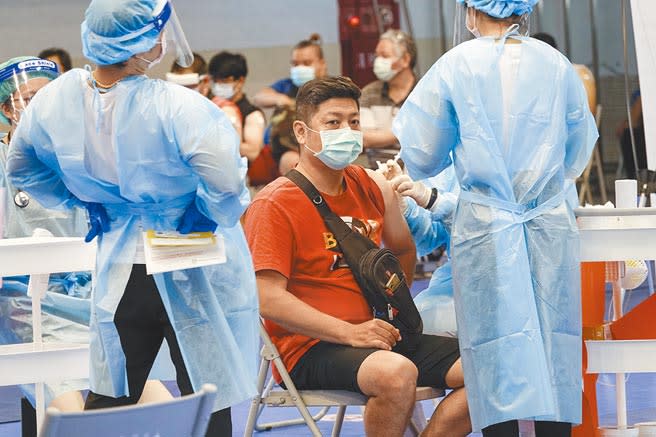 特權疫苗疑雲不斷，民眾想打1劑疫苗都得搶破頭，圖為台北市內湖高工接種站8日施打莫德納疫苗，一名護理人員(左)利用空檔站著伸展筋骨，放鬆一下。(黃子明攝)