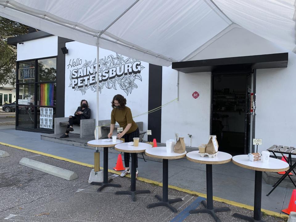 Sarah Weaver, owner of Bandit Coffee in St. Petersburg, Fla., places online orders on a pick up table outside the shop in this undated photo. The shop closed to customers on March 16, 2020, and Weaver quickly pivoted to contactless, curbside pickup orders — which was no small feat. Pre-pandemic, Bandit didn't have a phone and didn't take orders online for their carefully sourced, house roasted coffee. Now, nine months later, most customers order online and pick up at a table under a tent. (Sarah Weaver via AP)