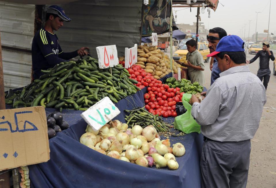 In this photo taken Friday, May 9, 2014, shoppers buy fresh vegetables in Jamila market in Baghdad, Iraq. Fighting in Iraq’s western Anbar province, now in its fifth month, appears to have bogged down, with government forces unable to drive out Islamic militants who took over one of the area’s main cities. But the impact is being felt much further, with the repercussions rippling through the country’s economy to hit consumers and businesses. Fighting has also disrupted shipping, inflating prices of goods in Baghdad and elsewhere. (AP Photo/ Karim Kadim)