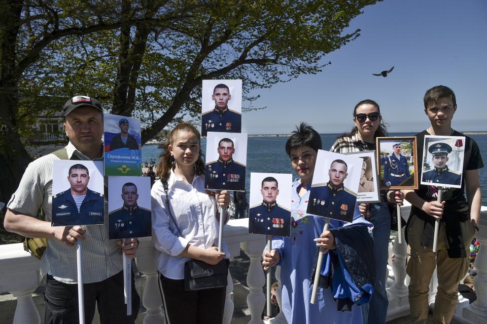 FILE - Relatives of servicemen who died during the Russian Special military operation in Donbas pose for a photo holding portraits of Russian soldiers killed during a fighting in Ukraine, after attending the Immortal Regiment march through a street marking the 77th anniversary of the end of World War II, in Sevastopol, Crimea, May 9, 2022. Nearly 50,000 Russian soldiers have died in the war in Ukraine, according to a new statistical analysis. (AP Photo, File)