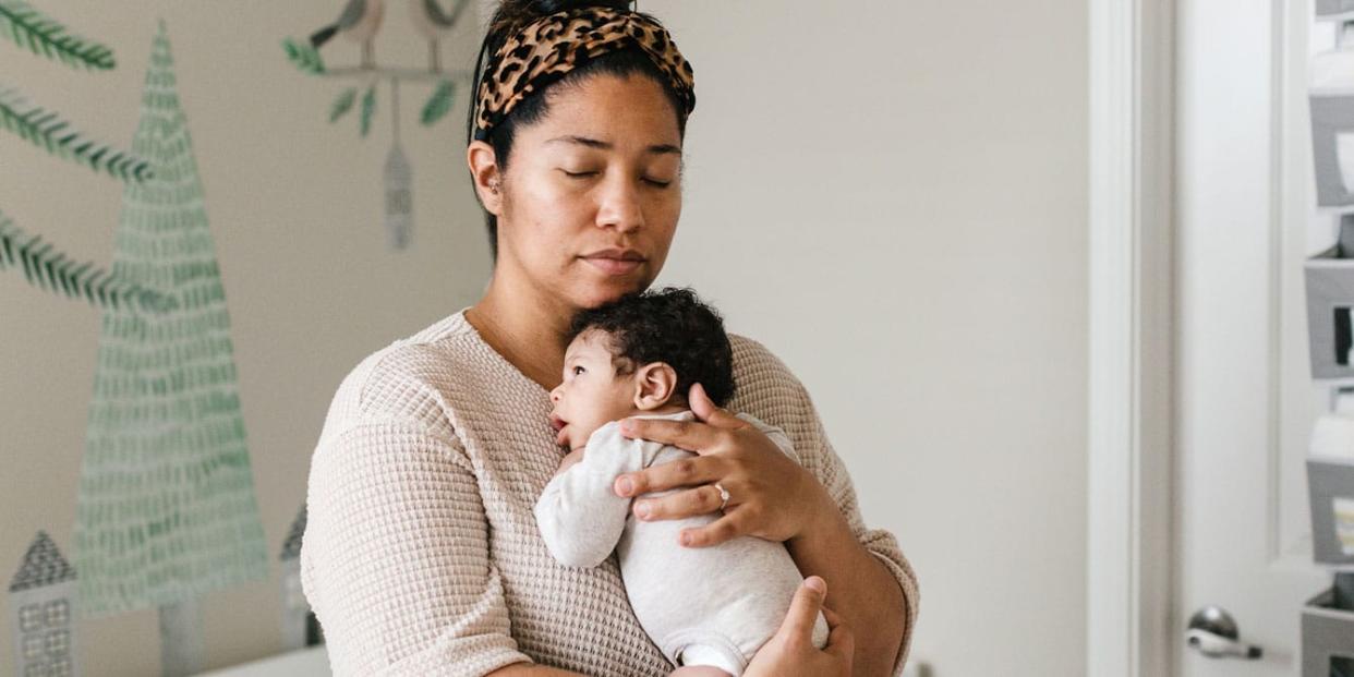 mom holding her newborn baby in a nursery - first of my friends to have a baby