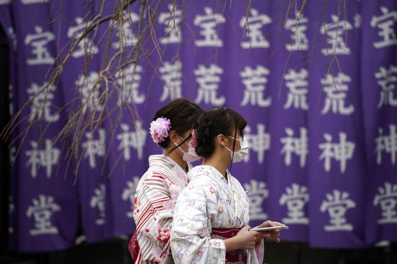 日本疫情嚴重，東京兩名女性遊客也戴著口罩。（美聯社）