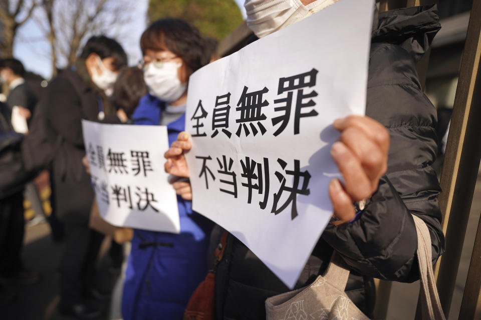 Yoshiko Furukawa, left, and Etsuko Kudo, right, supporters of the plaintiff hold a cloth sign that reads "All not guilty, Unfair judgment," outside of the Tokyo High Court in Tokyo Wednesday, Jan. 18, 2023. The court on Wednesday found three former executives of Tokyo Electric Power Company not guilty of negligence over the 2011 Fukushima nuclear meltdowns and subsequent deaths of more than 40 elderly residents during their forced evacuation. (AP Photo/Eugene Hoshiko)