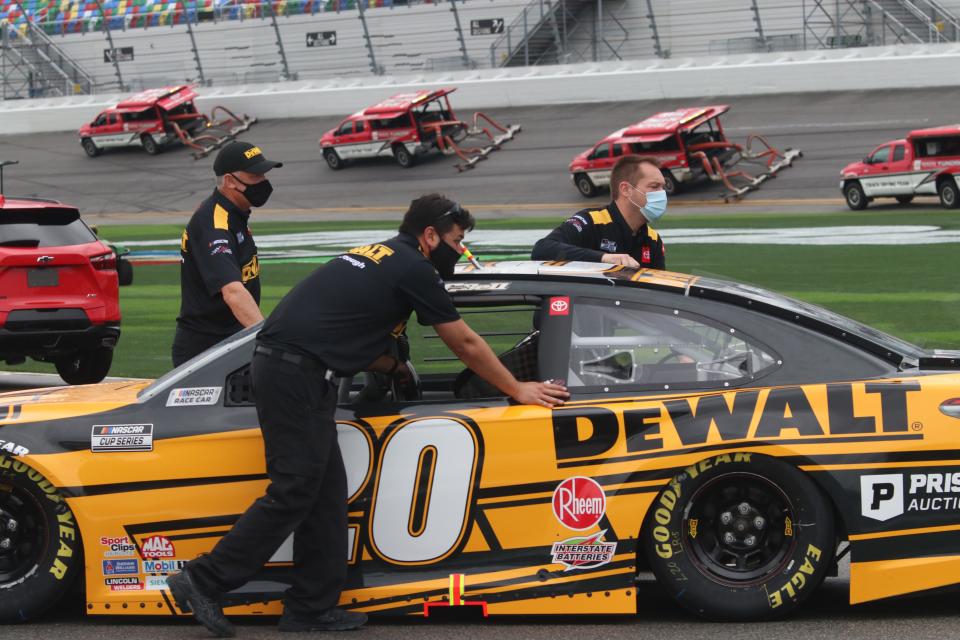 Crew members ready the No. 20 Toyota of Christopher Bell as Air Titans work the track in the background at Daytona International Speedway on Sunday, Feb. 14, 2021.