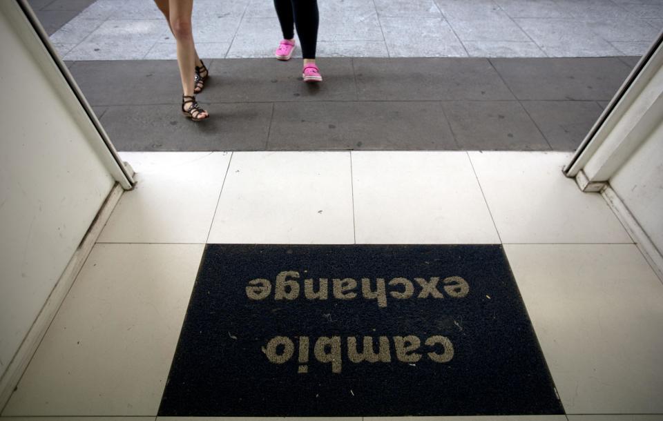 Two women enter a foreign exchange business in Buenos Aires, Argentina, Monday, Jan. 27, 2014. The Argentine government announced Friday it was relaxing restrictions on the purchase of U.S. dollars. The measure would start taking effect Monday, allowing Argentines to buy dollars for personal savings, reversing a 2012 restriction. (AP Photo/Natacha Pisarenko)