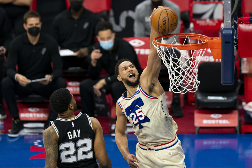 Philadelphia 76ers' Ben Simmons, right, goes up for a dunk as he passes San Antonio Spurs' Rudy Gay, left, during the first half of an NBA basketball game, Sunday, March 14, 2021, in Philadelphia. (AP Photo/Chris Szagola)