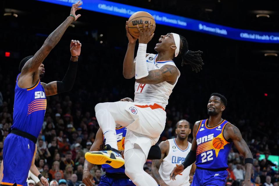 Clippers' Terance Mann drives to the basket between Phoenix Suns' Torrey Craig and Deandre Ayton.