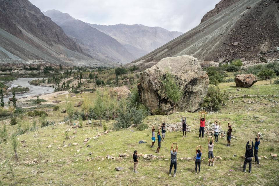 A group of climbers in a mountain valley, standing in a circle and stretching.