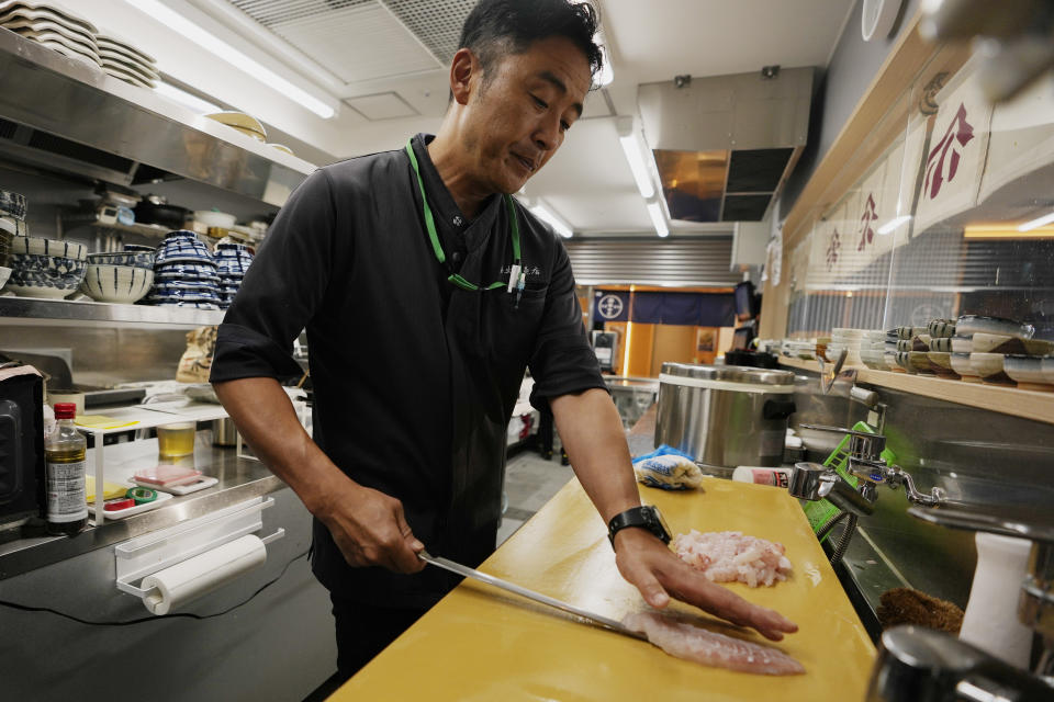 Katsumasa Okawa, owner of a fish store and a restaurant, cuts flounder meat as he prepares at his restaurant in Iwaki, northeastern Japan, Thursday, July 13, 2023. Okawa said those tanks containing contaminated water at the damaged Fukushima nuclear power plant bothers him more than the treated water release into the sea. He wants to have them removed as soon as possible, especially after seeing "immense" tanks occupying much of the plant complex during his visit a few years ago. (AP Photo/Hiro Komae)
