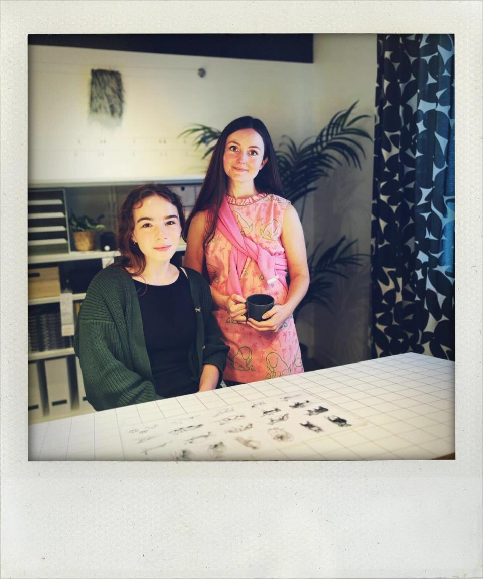 A seated woman and a standing woman in an Ikea model workspace.