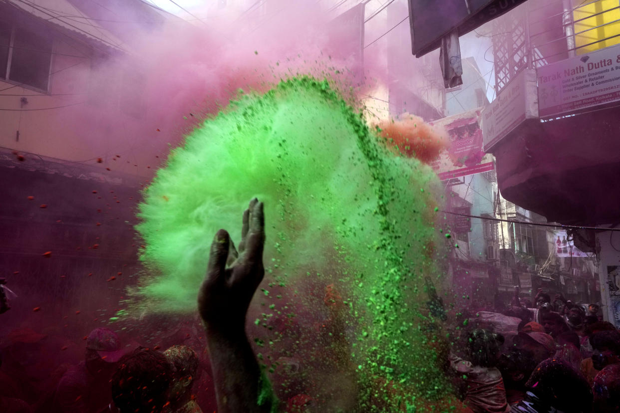 A devotee throws colored powder to others during celebration of the Holi festival on the onset of spring in Kolkata, India, Sunday, March 5, 2023. Millions of Indians on Wednesday celebrated the ''Holi" festival, dancing to the beat of drums and smearing each other with green, yellow and red colors and exchanging sweets in homes, parks and streets. Free from mask and other COVID-19 restrictions after two years, they also drenched each other with colored water(AP Photo/Bikas Das)