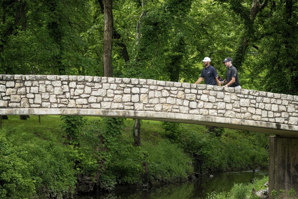 Captain Dustin Johnson, left, of 4Aces GC, and captain Bubba Watson, right, of RangeGoats GC, walks over a bridge on the 12th hole during the final round of LIV Golf Tulsa at Cedar Ridge Country Club, Sunday, May 14, 2023, in Broken Arrow, Okla. (Charles Laberge/LIV Golf via AP)