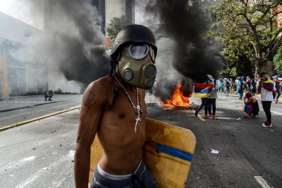 An opposition activist wearing&nbsp;a helmet and gas mask stands near a burning motorbike on May 31.