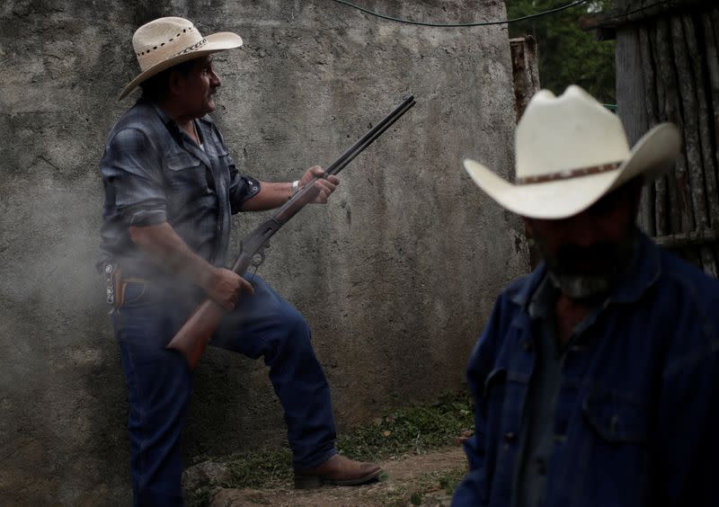 Paulo Ramirez holds a rifle carbine 30-30 during a family meeting at his farm in Jalpan de Serra