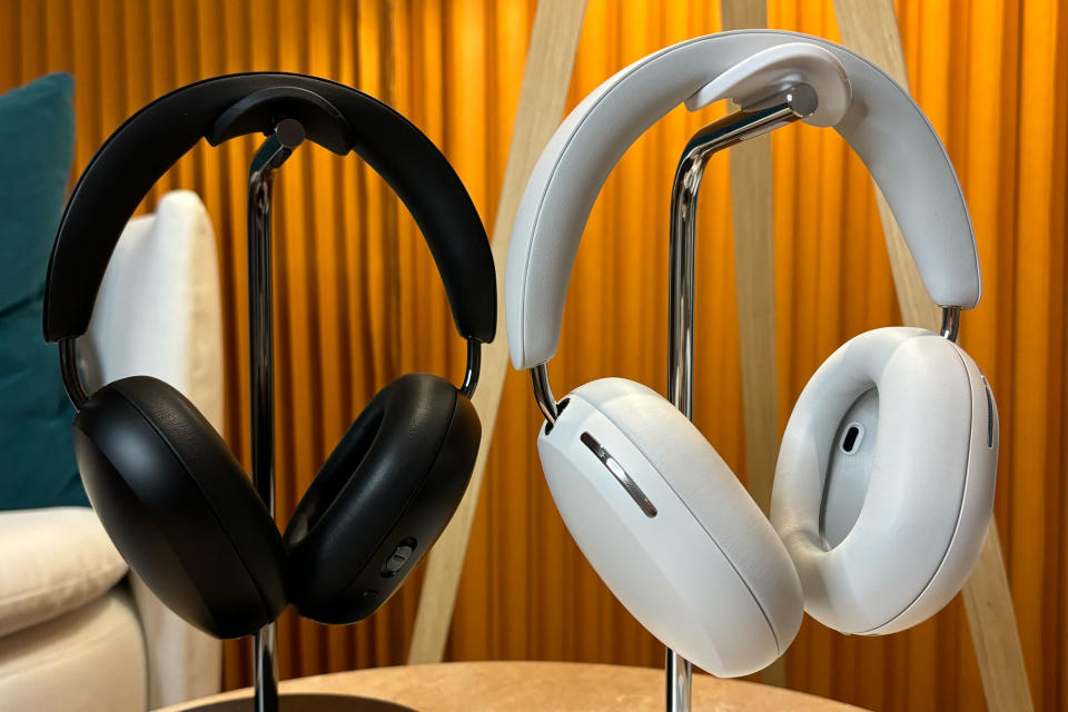 <p>Two pairs of headphones, one black and one white, hanging on stands.</p>
