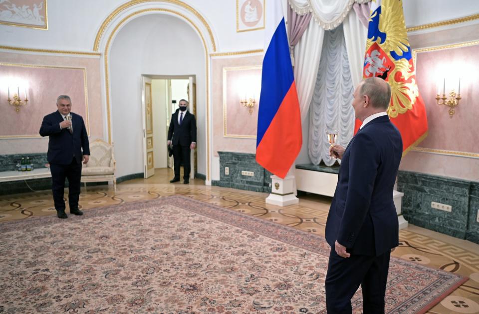 Putin and Hungarian Prime Minister Viktor Orbán, on opposite sides of a large rug, toast each other.