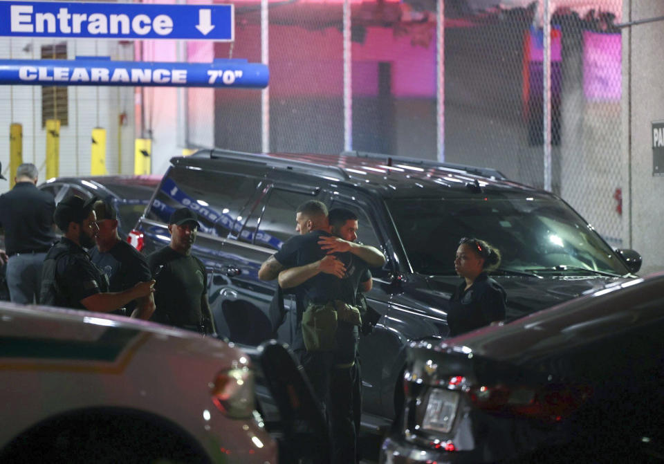 Police officers and other officials stand outside the Ryder Trauma Center after a Miami-Dade police officer was shot in an exchange of gunfire during a car chase with an armed robbery suspect, Monday, Aug. 15, 2022, in Miami. (Alie Skowronski/Miami Herald via AP)