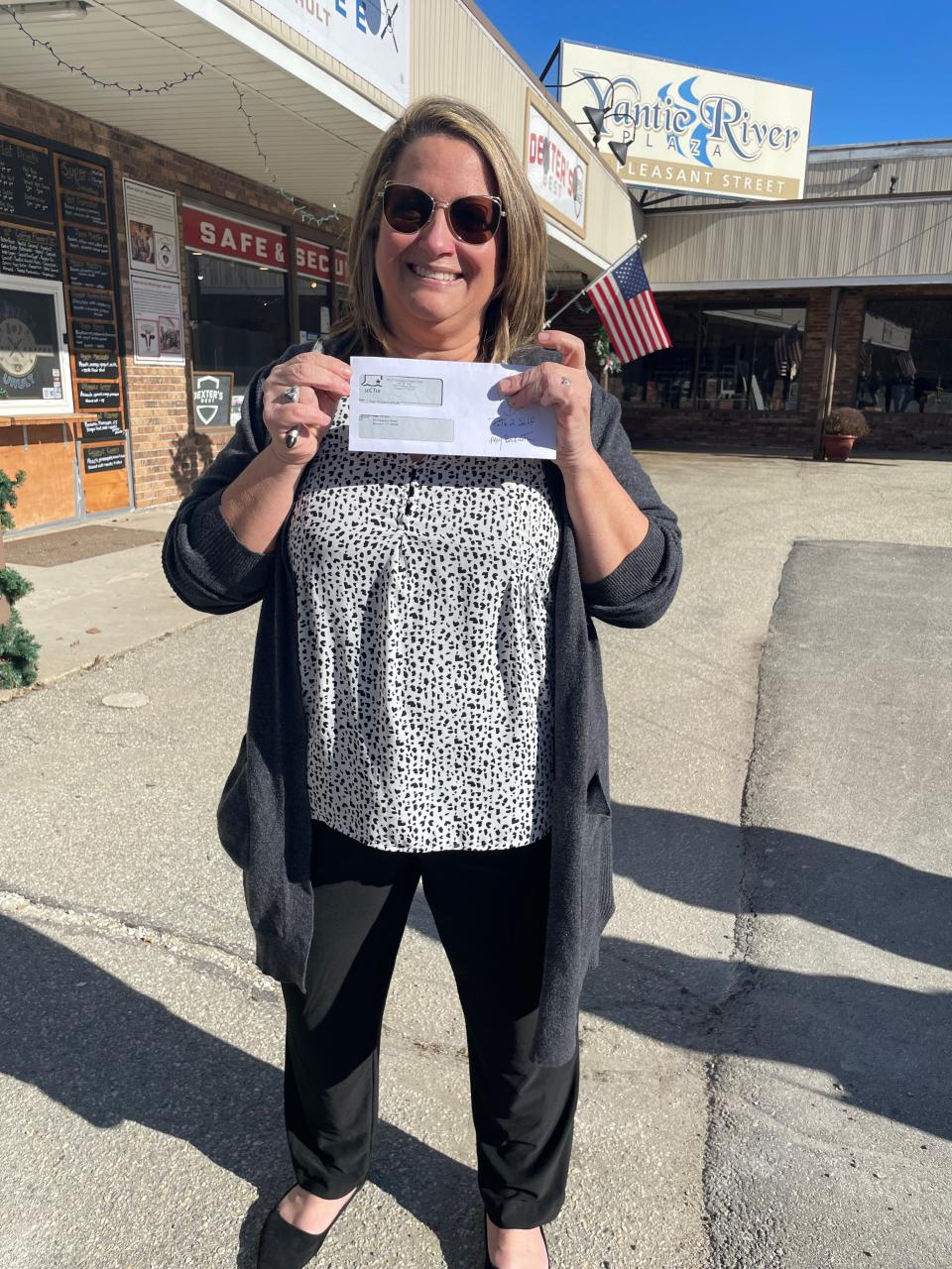 Amy Beckwith, co-owner of Path to Self Wellness, holding a check. Her business is one of 11 businesses to receive a flood relief micro grant on Tuesday.