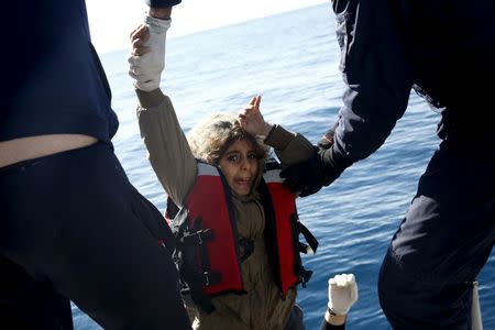 Greek Coast Guard officers move a girl from a dinghy carrying refugees and migrants aboard the Ayios Efstratios Coast Guard vessel, during a rescue operation in the open sea between the Turkish coast and the Greek island of Lesbos, February 8, 2016. REUTERS/Giorgos Moutafis