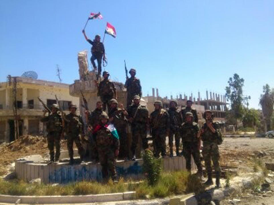 FILE - In this Wednesday, June 5, 2013 file photo released by the Syrian official news agency SANA, Syrian army troops hold up national flags in the town of Qusair, near the Lebanon border, Homs province, Syria. Two years ago, it seemed almost inevitable that President Bashar Assad would be toppled. Almost no one thinks that now. As he prepares for elections through which he is set to claim another seven-year mandate for himself, the momentum in the civil war is clearly in Assad's favor. (AP Photo/SANA, File)