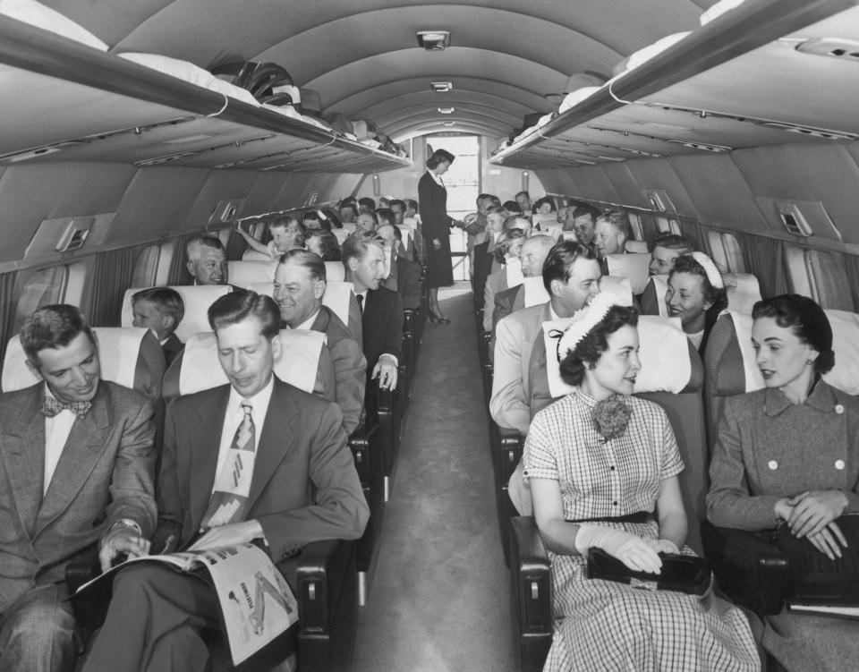 Passengers, seated two to a row, talk with their inflight neighbors aboard a Mainliner Convair aircraft as the flight attendant works at the back of the plane in the late 1940s.