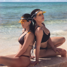 <p>Kim and Kourtney wear matching black bikinis and yellow visors. So chic.</p>