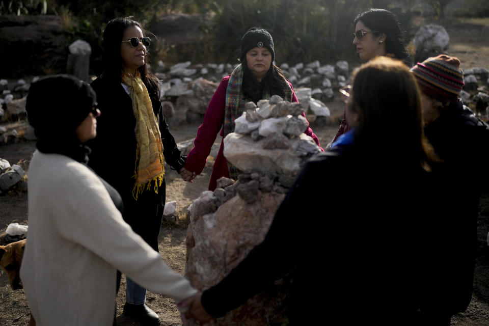 Brazilians Gilma Ribeiro, center, and Neiva Santos, second left, hold hands standing in a circle at the heart of a stone labyrinth in the Pueblo Encanto spiritual theme park in Capilla del Monte, Argentina, Wednesday, July 19, 2023. In the pope’s homeland of Argentina, Catholics have been renouncing the faith and joining the growing ranks of the religiously unaffiliated. Commonly known as the “nones,” they describe themselves as atheists, agnostics, spiritual but not religious, or simply: “nothing in particular.” (AP Photo/Natacha Pisarenko)