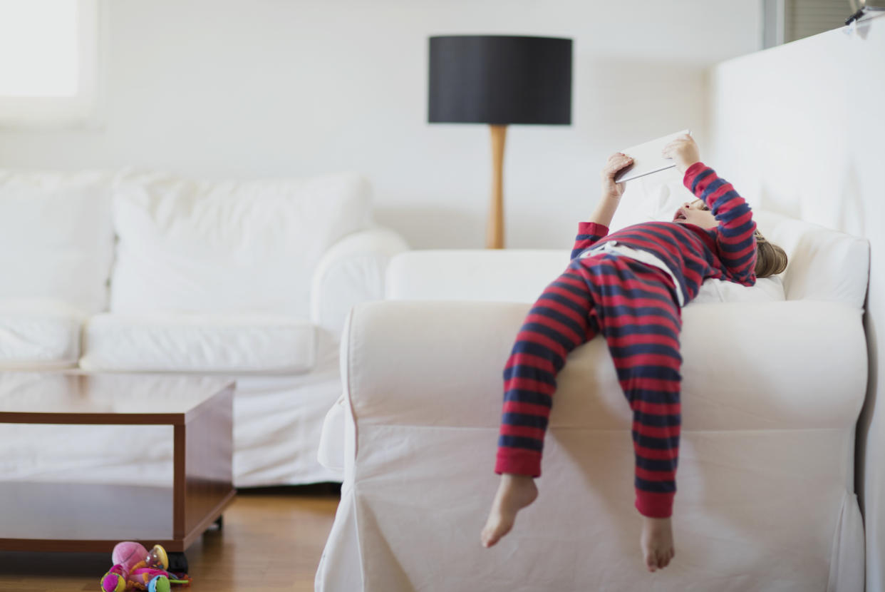 Child lying on a sofa using a mobile phone. (Getty Images)