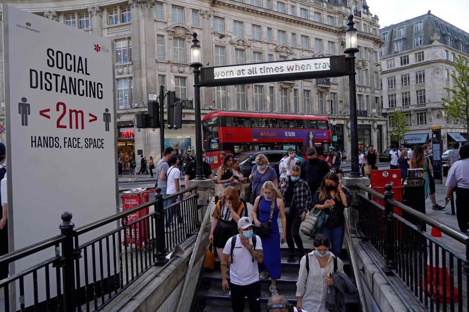 Commuters wearing face coverings enter Oxford Circus Tube station (AFP via Getty Images)