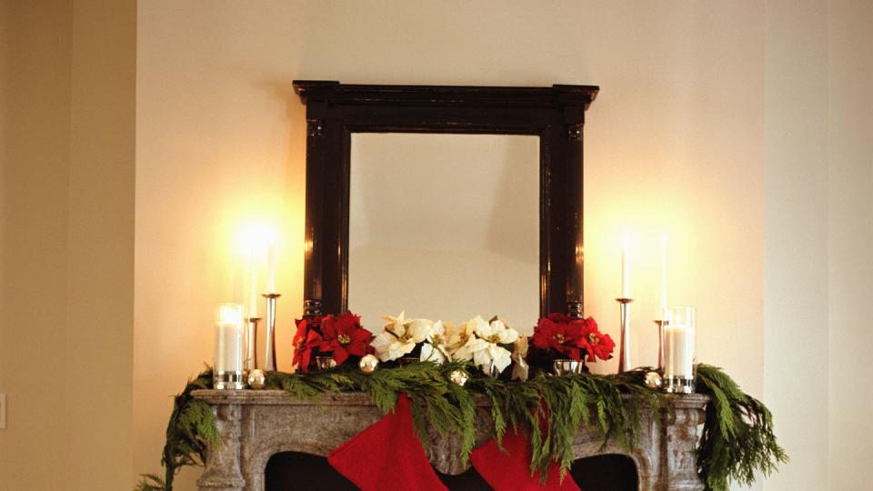 fireplace decorated with christmas stockings and poinsettias