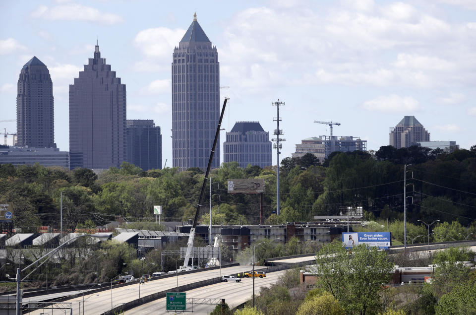 Construction crews work on a section of an overpass that collapsed from a large fire on Interstate 85 as the Midtown skyline stands in the background in Atlanta, Friday, March 31, 2017. Atlanta's dreadful rush-hour traffic got even worse Friday, the morning after a raging fire underneath Interstate 85 collapsed an elevated portion of the highway and shut down the heavily traveled route through the heart of the city. (AP Photo/David Goldman)