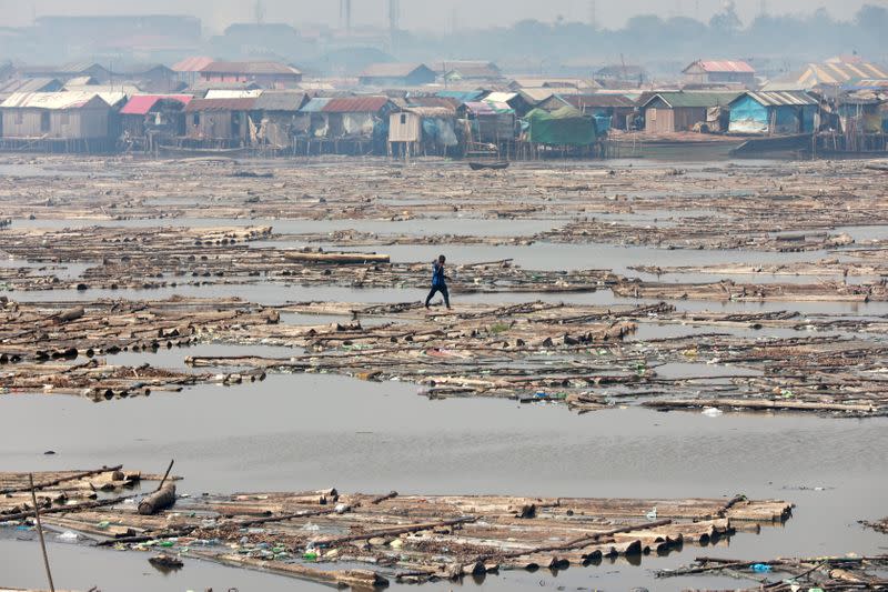 A man walks on logs of wood placed on the river at the Makoko community in Lagos