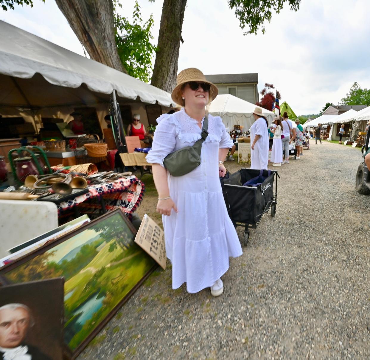 Leah Sandman of New Haven, Connecticut, pulls a wagon past vendors at stalls at Brimfield Antique Flea Market on Wednesday.