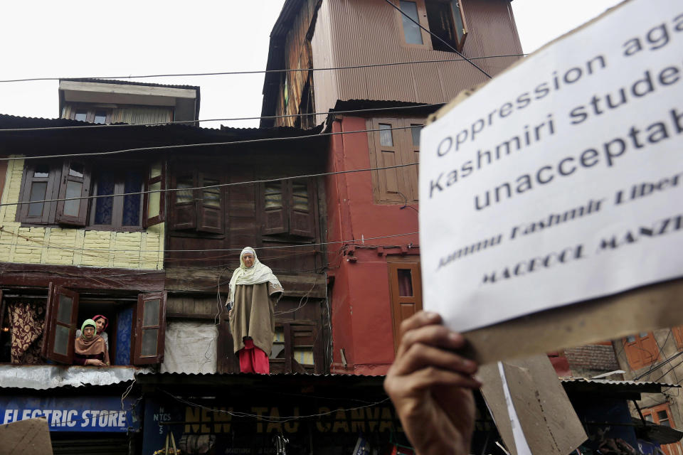 Kashmiri Muslim women watch supporters of Jammu Kashmir Liberation Front (JKLF) chairman Yasin Malik shout pro freedom slogans during a protest in Srinagar, India, Friday, March 7, 2014. Dozens of Muslim students from the disputed Indian territory of Kashmir were expelled from their university and briefly threatened with sedition charges because they cheered for the Pakistani cricket team during a televised match against archrival India, police said Thursday, while the Indian state's elected leader called for leniency. (AP Photo/Dar Yasin)