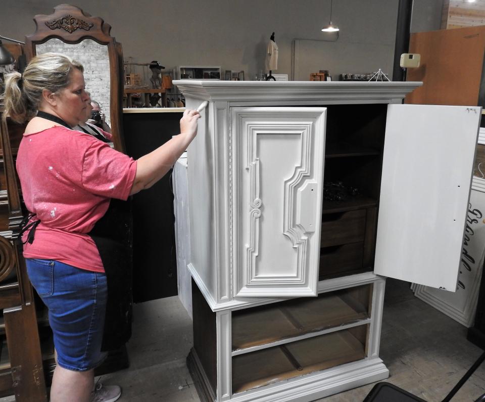 Jill Sheridan paints an armoire, a custom job from a customer. She owns Rust Décor with her husband.