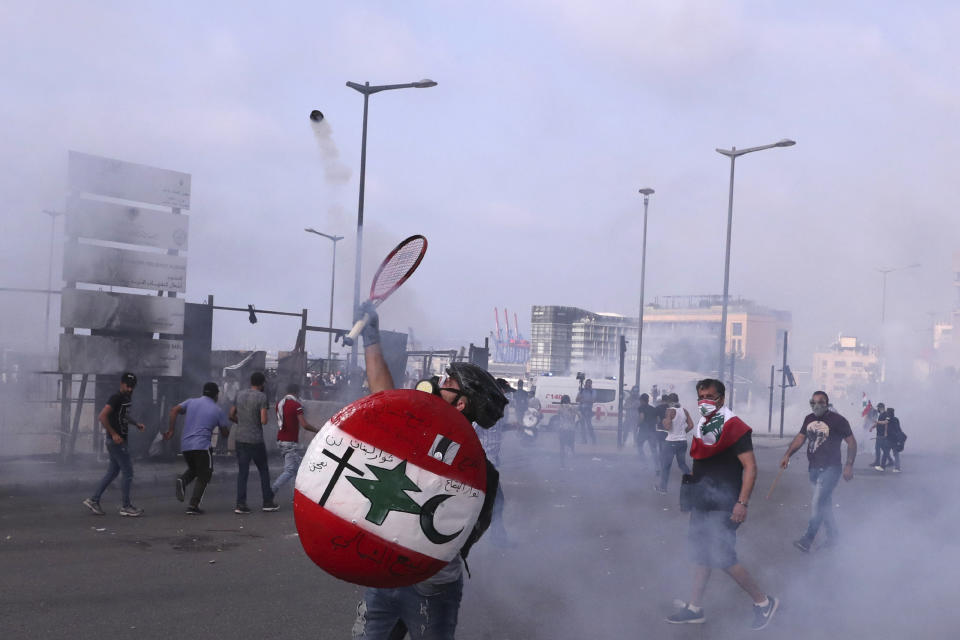 An anti-government protester throws back tear gas at riot policemen with a tennis racket during ongoing protests against the Lebanese government, in downtown Beirut, Lebanon, Saturday, June 6, 2020. Hundreds of Lebanese demonstrators gathered in central Beirut Saturday, hoping to reboot nationwide anti-government protests that began late last year amid an unprecedented economic and financial crisis. (AP Photo/Bilal Hussein)