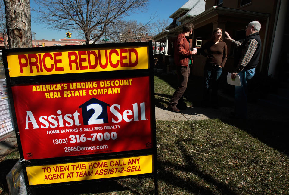 (L-R) Prospective home buyers Lars Kalnajs and Leah Fuchs talk to real estate broker John Skrabec of Live Urban Real Estate in the yard of a home that has been reduced in price in Denver, Colorado. (Credit: Chris Hondros, Getty Images)