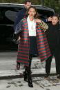 <p>In an oversized striped coat, Chanel bag, white blouse, black pants and black Dior over-the-knee boots in Paris</p>