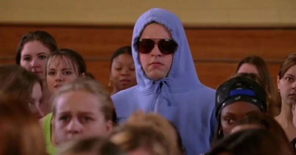 A queer Halloween costume for 2023. The image shows Damien in Mean Girls. He wears a baby blue hoodie with the hood up and tied tight around his face. He also wears sunglasses and has a straight face.