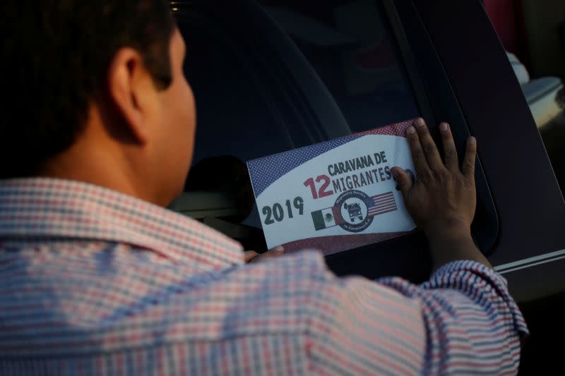 A man places a sticker of the 12th Caravan of Migrants on his car in Laredo, Texas