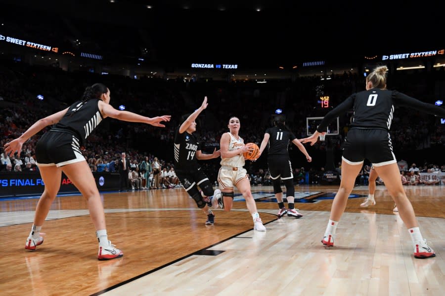 Texas guard Shaylee Gonzales, center, drives to the basket as Gonzaga guard Kaylynne Truong (14) defends during the first half of a Sweet 16 college basketball game in the women’s NCAA Tournament, Friday, March 29, 2024, in Portland, Ore. (AP Photo/Steve Dykes)