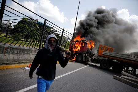 A demonstrator gestures in front of a truck set on fire on a highway during a rally against Venezuela's President Nicolas Maduro's Government in Caracas, Venezuela, June 23, 2017. REUTERS/Ivan Alvarado