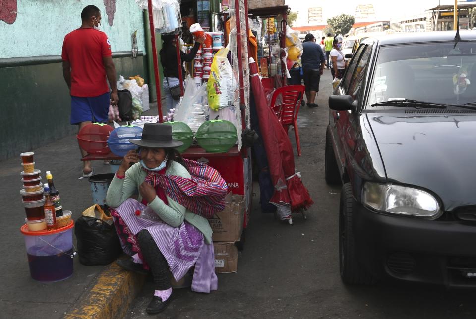 A honey vendor talks on her cellphone outside of a market in Lima, Peru, Sunday, Jan. 31, 2021. Peruvian authorities are instituting a complete lockdown in multiple regions including the capital due to a resurgence in COVID-19 cases that has taxed healthcare services to their maximum capacity. (AP Photo/Martin Mejia)