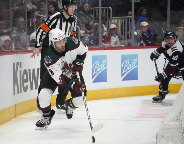 Arizona Coyotes center Nick Schmaltz, front left, looks to pass the puck as Colorado Avalanche defenseman Samuel Girard, right, pursues in the second period of an NHL hockey game Friday, March 24, 2023, in downtown Denver. (AP Photo/David Zalubowski)