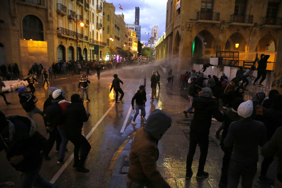 Anti-government protesters clash with the riot police during ongoing protests in Beirut, Lebanon, Wednesday, Jan. 22, 2020. Lebanon's new government held its first meeting Wednesday, a day after it was formed following a three-month political vacuum, with the prime minister saying his Cabinet will adopt financial and economic methods different than those of previous governments. (AP Photo/Bilal Hussein)