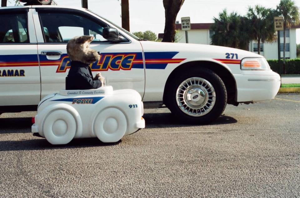A robotic dog drives a miniature Miramar police car next to a real one.