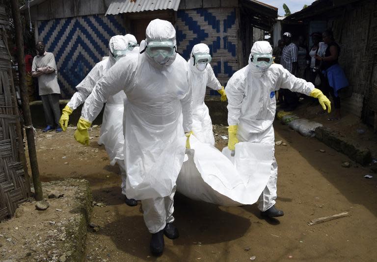 Red Cross workers carry away the body of a person suspected of dying from the Ebola virus, in the Liberian capital Monrovia, on October 4, 2014