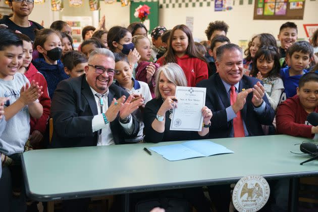 Gov. Michelle Lujan Grisham, center, holds a bill she signed at a school in Santa Fe, New Mexico, on Monday. The legislation provides universal free school meals for students in the state.