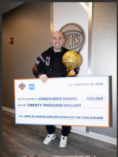 Jr. Knicks Coach of the Year Mike Simmel displays $20,000 check for his work with special needs kids.