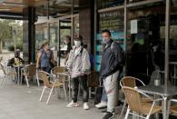 People wearing protective face masks stand at Usera neighbourhood in Madrid